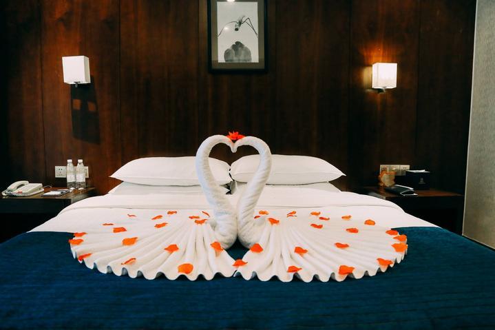 床上专门用毛巾布置了两只天鹅的造型还撒上了玫瑰花很浪漫的感觉.