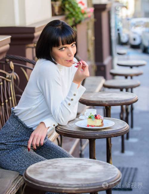 女人迷人优雅的黑发女人吃美食蛋糕咖啡厅露台背景.愉快的时间和放松.