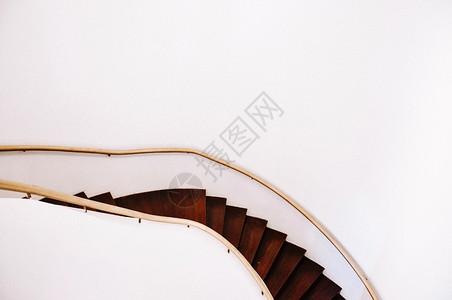 楼梯扶手的古老的木螺旋楼梯扶手和大白墙空间背景