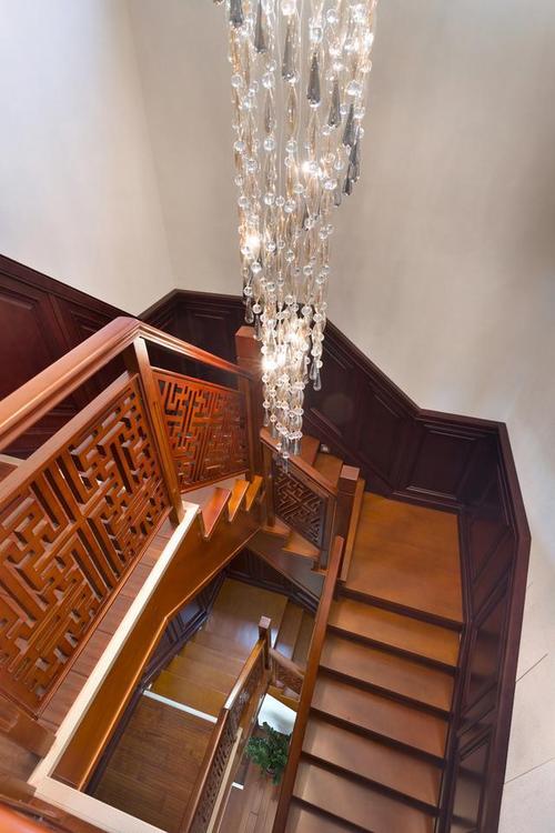楼梯中间顶部装一款精致的水晶长吊灯让这个高高的楼梯井显得不那么