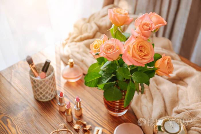 房间木桌上放着玫瑰花和化妆化妆品