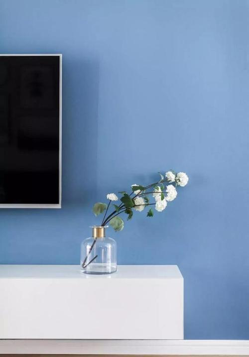 蓝色电视背景墙木作架空白色电视柜呈现简约氛围.
