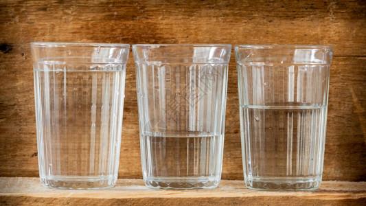 新鲜的清爽喝三杯水用自然光照亮放在木板上的三杯水图片素材