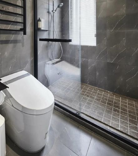 浴室内部以灰色的墙面地面砖的空间基础结合黑色的淋浴房边框五金件
