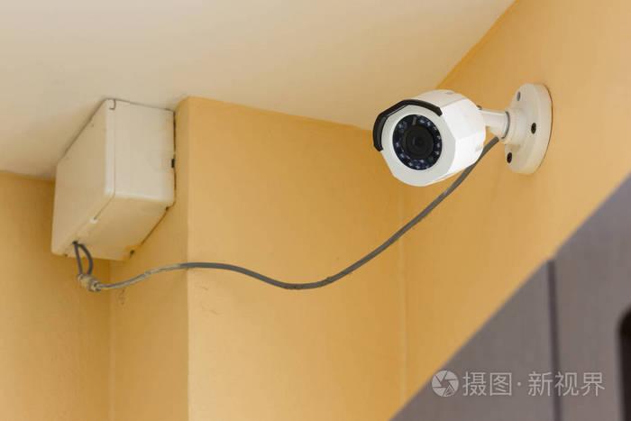 在室内的橙色水泥墙上运行的闭路电视监控摄像头