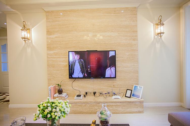 电视背景墙利用米黄洞石既增加整体空间的协调又利用两边的壁灯