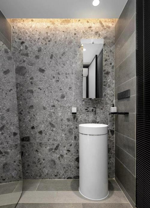 卫生间在灰色水磨石墙面搭配暖灰色地面砖还有一个小巧的一体式洗手