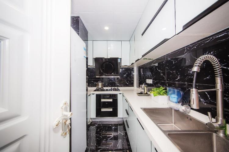 白色的橱柜和大理石台面与黑色地砖形成对比反而扩大厨房的空间感.
