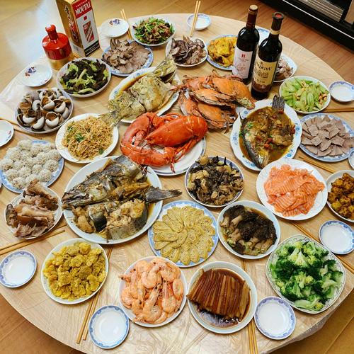 丰盛的年夜饭餐桌上有龙虾海参螃蟹三文鱼榛蘑土鸡江米丸子西芹