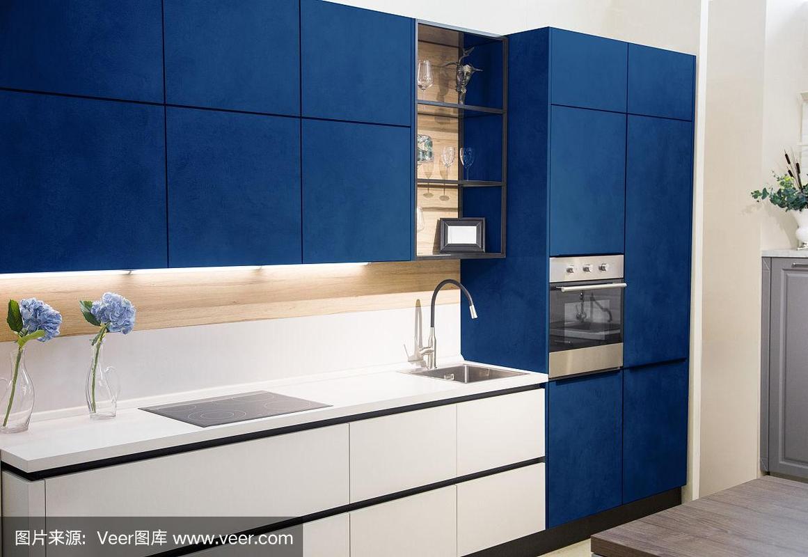 现代的蓝色厨房内部白色砖墙木制台面内置水槽和炊具.