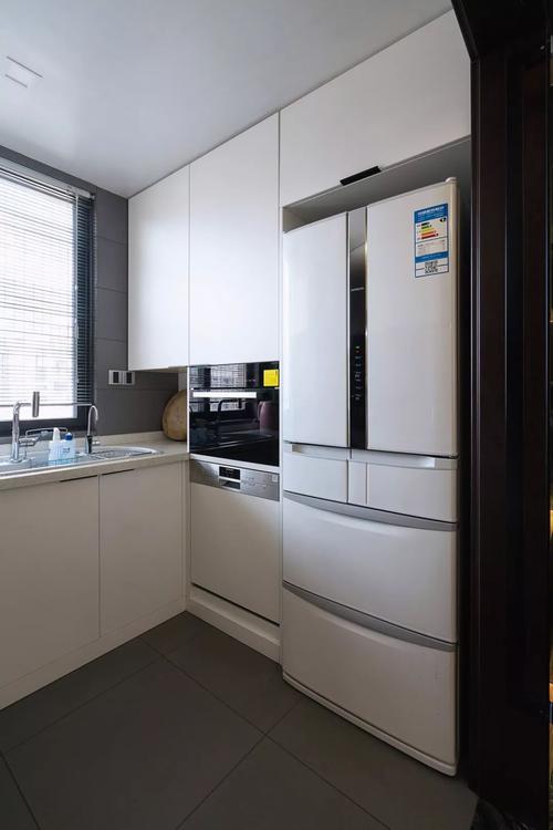 厨房以白色橱柜门板搭配黑色的电器还有灰色的墙面砖装扮出一个