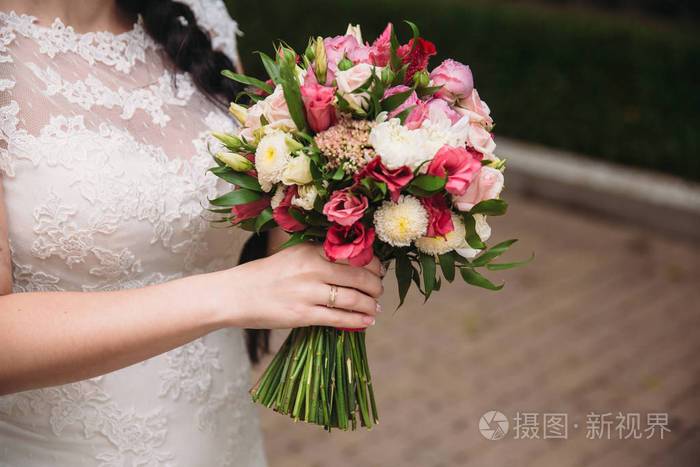 新娘手里拿着白色和粉色的玫瑰的美丽婚礼花束的特写植物种类的概念